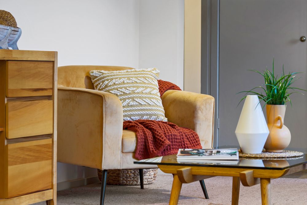 Illustrative ochre upholstered armchair with a patterned cushion