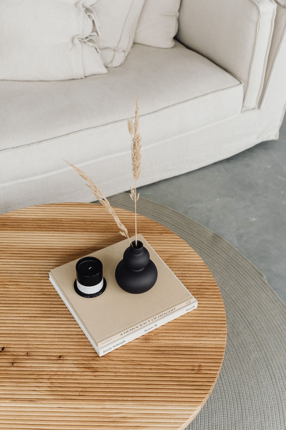 Illustrative oval wooden coffee table styled with books and a black vase